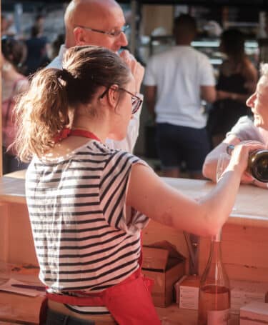 Jeune femme servant du vin dans un bar éphémère