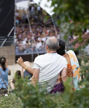 Couple assis dans l'herbe au Jardin de Cybèle, écoutant un concert