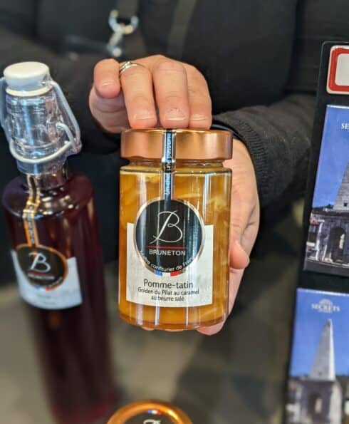 Mains présentant un pot de confitures de la maison Bruneton