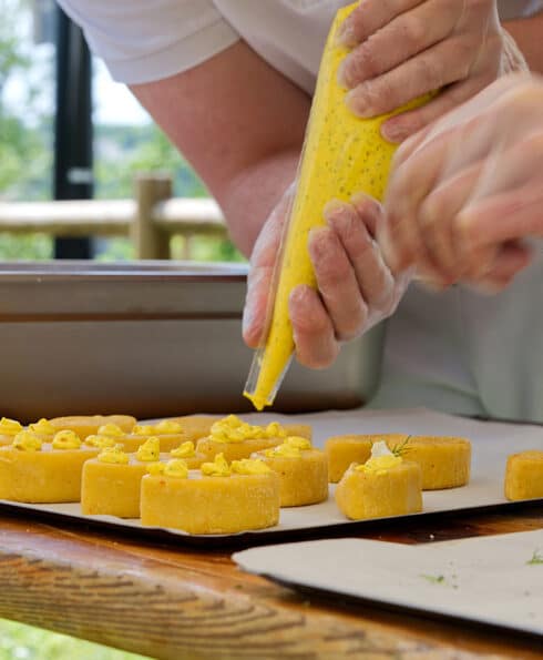 Mains en train de pocher une crème sur des petits fours